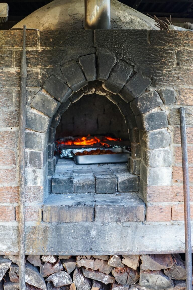 Traditional brick oven with glowing embers and baking tray inside, perfect for rustic cooking.